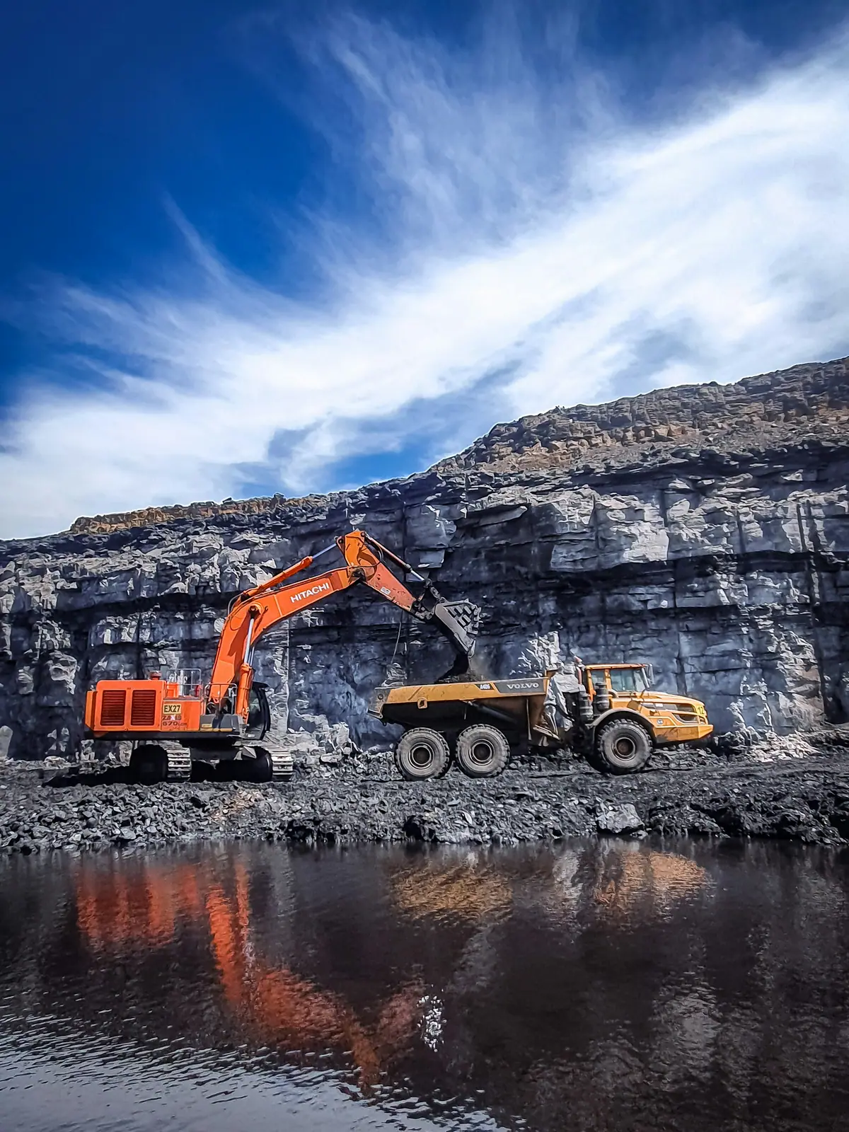 An excavator loading a dump truck at a mine face